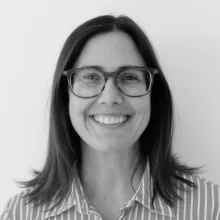 Black and White headshot of a smiling woman with shoulder-length hair and glasses