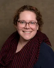 attractive curly-haired woman in a blue and red striped scarf